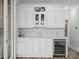 The wet bar has bright white cabinets, wine fridge, glass shelving, and stone backsplash at 4049 Shadowbrook Rd, Waxhaw, NC 28173