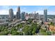 Panoramic view of the Charlotte skyline with modern buildings and lush green trees in the foreground on a clear, sunny day at 409 W 8Th St, Charlotte, NC 28202