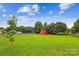 Spacious backyard with a vibrant red shed and mature trees surrounded by lush greenery at 4527 Marshall Ct, Monroe, NC 28110