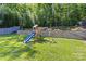 Landscaped backyard featuring a wooden playset, green grass, a retaining wall, and privacy fencing at 6013 Camile Ct, Charlotte, NC 28226