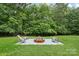 Backyard fire pit surrounded by green grass and lush trees, perfect for outdoor gatherings at 7017 S Providence Rd, Waxhaw, NC 28173