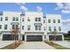 New construction three-story townhome with black garage doors, stone accents, and a concrete driveway at 9214 Delancey Ln # 62, Concord, NC 28027