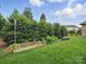 Backyard featuring manicured hedges, garden beds, and lush green grass at 1004 Fairbanks Ct, Indian Trail, NC 28079