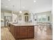 Spacious kitchen featuring an island with granite countertops, wood cabinets, and a stainless steel sink at 1004 Fairbanks Ct, Indian Trail, NC 28079