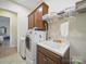 Functional laundry room with washer, dryer, sink, storage cabinets, and hanging rack at 1004 Fairbanks Ct, Indian Trail, NC 28079