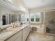 Bright main bathroom with double sinks, granite countertops, a tub, and tiled walk-in shower at 1004 Fairbanks Ct, Indian Trail, NC 28079