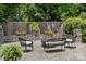 Seating area in backyard featuring wicker furniture, lush greenery, and a stone wall at 106 Phifer St, Fort Mill, SC 29715