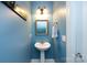 Charming half bathroom with blue walls, pedestal sink, decorative mirror, and sconce lighting at 139 Harper Lee St, Davidson, NC 28036