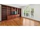 Living Room showcases built-in shelving, hardwood floors, and a light filled window at 15216 Ballantyne Country Club Dr, Charlotte, NC 28277