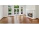 Bright living room with hardwood floors, fireplace, and backyard pool view at 15216 Ballantyne Country Club Dr, Charlotte, NC 28277