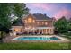 Stunning backyard oasis with a sparkling pool, patio, and ample seating at dusk at 15216 Ballantyne Country Club Dr, Charlotte, NC 28277