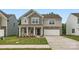 Charming two-story home with stone accents, a covered porch, a two-car garage, and a well-manicured lawn at 1545 Cottage Creek Dr, Bessemer City, NC 28016
