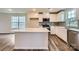 Modern kitchen with white cabinets, stainless steel appliances, gray backsplash, and an island with a quartz countertop at 1545 Cottage Creek Dr, Bessemer City, NC 28016