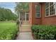 Exterior view of a red brick home with a screened-in porch and garden at 1912 Windmere Dr, Monroe, NC 28110