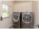 Laundry room with modern washer and dryer, white cabinets, and a window for natural light at 1912 Windmere Dr, Monroe, NC 28110