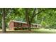 View of the exterior of the brick home showing mature trees and beautiful green lawn at 240 China Grove Rd, China Grove, NC 28123