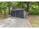 Exterior shot of the detached two car garage with dark gray doors and gravel driveway at 240 China Grove Rd, China Grove, NC 28123