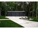 The exterior of a three-car garage with black doors, a firepit, and green lawn at 3020 Brooks Mill Ln, Wingate, NC 28174