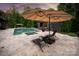 Relaxing patio space with lounge chairs, umbrella, pool and backyard in background at 3020 Brooks Mill Ln, Wingate, NC 28174