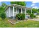 Cozy home with a quaint front porch and blue door, complemented by lush landscaping at 3400 Reid Ave, Charlotte, NC 28208