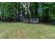 Large backyard with a wooden deck and storage shed surrounded by mature trees at 5233 Great Wagon Rd, Charlotte, NC 28215
