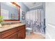 Well-lit bathroom with granite countertops, wood vanity, framed mirror, and shower-tub combo with floral curtain at 560 Blue Sky Dr, Dallas, NC 28034
