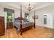 Inviting bedroom with four-poster bed, hardwood floors, and ensuite bathroom access, bathed in natural light at 560 Blue Sky Dr, Dallas, NC 28034