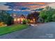 Charming home featuring a stone and siding exterior, covered porch, and mature landscaping at sunset at 560 Blue Sky Dr, Dallas, NC 28034