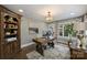 A well-appointed office with custom shelving, hardwood floors, a large window, and stylish light fixture at 5721 Ballinard Ln, Charlotte, NC 28277