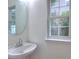 Bathroom featuring a pedestal sink, round mirror, and a window providing natural light at 6310 Trevor Simpson Dr, Indian Trail, NC 28079