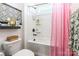 Well-lit bathroom with a combination shower and bathtub, featuring tiled accents and a pink shower curtain at 651 Melville Dr, Rock Hill, SC 29732