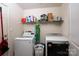 Functional laundry room with modern washer, dryer, storage shelf, and organized cleaning supplies at 792 Carolina Mill Cir, Lincolnton, NC 28092