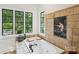 Bright bathroom with a garden tub, stone tile accent wall, and a view of the lush, wooded outdoors at 9184 Greenwood Rd, Terrell, NC 28682