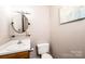 Compact half-bathroom with a round mirror, white sink, and toilet, offering essential convenience at 102 Brandywine Ne Dr # O-3, Conover, NC 28613