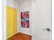 Hallway with hardwood floors, colorful artwork, and bright yellow door at 115 E Park Ave # 409, Charlotte, NC 28203