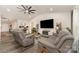 Open-concept living room with gray sofas, modern fan, and TV, offering a cozy gathering space at 1405 Amberlight Cir, Salisbury, NC 28144