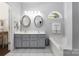 Well-lit bathroom featuring dual sinks, a soaking tub, and a vanity with grey cabinetry at 14218 Springsure Ct, Huntersville, NC 28078