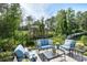 The patio features comfortable blue seating, a glass table, and a picturesque wooded backdrop for relaxation at 14531 Crosswater Ln, Charlotte, NC 28278