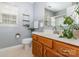 Cozy bathroom featuring a wooden vanity, white countertop, neutral tile flooring, and hanging plants at 1533 Moss Creek Dr, Harrisburg, NC 28075