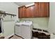 Functional laundry room with a washer, dryer, overhead cabinets, and storage baskets at 15929 Northstone Dr, Huntersville, NC 28078