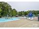 Community pool featuring a splash pad, lounge chairs and mature trees surrounding the area at 15929 Northstone Dr, Huntersville, NC 28078