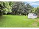 Expansive backyard featuring lush lawn, mature trees, and a storage shed on the right at 2421 Shamrock Dr, Charlotte, NC 28205