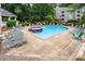 Community pool with multiple lounge chairs is surrounded by mature trees at 2512 Cranbrook Ln # 9, Charlotte, NC 28207