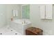 Bathroom with a marble-surround soaking tub and a leather ottoman, perfect for relaxation at 2516 Selwyn Ave, Charlotte, NC 28209