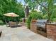 Stone patio with outdoor kitchen, fireplace, and dining area surrounded by greenery at 2516 Selwyn Ave, Charlotte, NC 28209