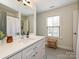 Bathroom featuring a white vanity, large mirror, penny tile flooring, a stool, and a window providing natural light at 2518 Pinckney Ave, Charlotte, NC 28205