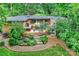 Aerial view of a backyard featuring a manicured lawn, patio with an outdoor kitchen and mature trees at 2600 Cloister Dr, Charlotte, NC 28211