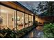 Large windows illuminate the interior of this home, with lush landscaping surrounding a stone walkway at 2600 Cloister Dr, Charlotte, NC 28211