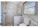 A bathroom featuring a marble-tiled shower with a glass enclosure and white fixtures at 29049 Snapper Pt, Tega Cay, SC 29708
