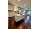 Open kitchen featuring white cabinets, an island with cooktop, and hardwood floors extending into the living space at 306 Sacco St, Belmont, NC 28012